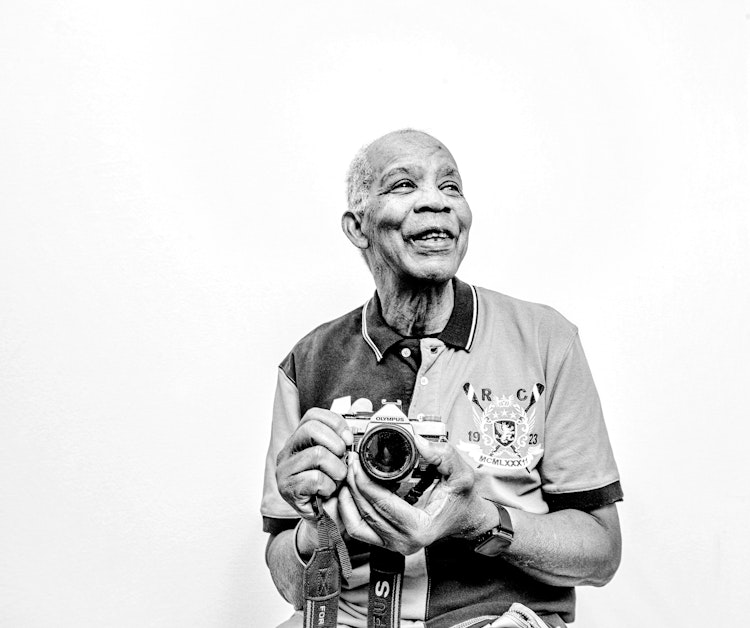 Black and white photo of Tony Powlett holding camera by John Ferguson